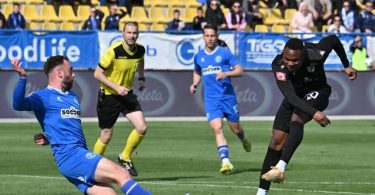 Fudbaler u plavoj majici driblira sa loptom tijekom fudbalske utakmice
