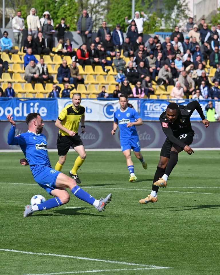 Fudbaler u plavoj majici driblira sa loptom tijekom fudbalske utakmice
