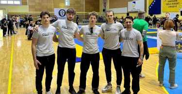 Grupa članova Poskoka u bijelim majicama pozira na sportskoj dvorani tijekom jiu-jitsu turnira