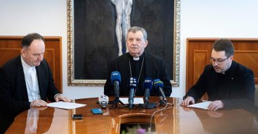 Tri biskupa sjedna pri stolu s mikrofonima na konferenciji za medije