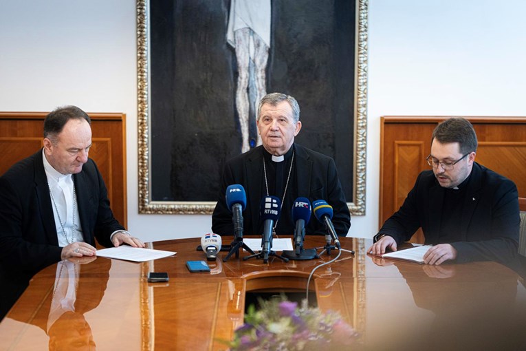 Tri biskupa sjedna pri stolu s mikrofonima na konferenciji za medije