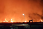 Noćni pogled na široki požar s plamenom i dimom na horizont, rasvjetljeno ulično svjetlo u prvom planu