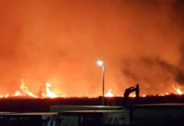 Noćni pogled na široki požar s plamenom i dimom na horizont, rasvjetljeno ulično svjetlo u prvom planu