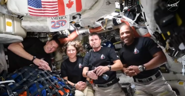 Skupina astronauta u svemirskoj stanici s američkom i kanadskom zastavom u pozadini