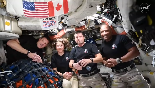 Skupina astronauta u svemirskoj stanici s američkom i kanadskom zastavom u pozadini
