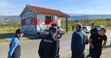 Policijski službenici stoje ispred murala s likom tijekom intervencije u Ortiješu
