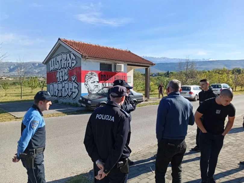 Policijski službenici stoje ispred murala s likom tijekom intervencije u Ortiješu