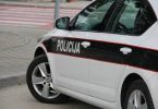 Bijelo-crno policijsko vozilo s natpisom Policija parkirano na cesti