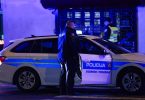 Policijski automobil i policajac tijekom noći ispred zgrade