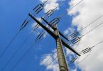 Betonski elektroenergetski stup sa više visokonaponskih vodova protiv plavog neba