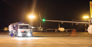 Kamion za prijevoz goriva s crijevoм povezan na avion tijekom noćnog punjenja na aerodromu