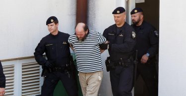 Policajci vode osumnjičenog muškarca u prugastoj majici tijekom uhićenja
