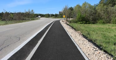 Novi asfaltni put sa betonskim rubnjacima i šljunčanom prugom uz cestu