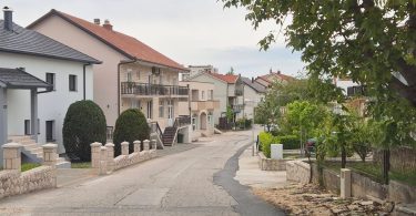 Prikaz ulice Stjepana Radića s kućama i zasađenim stablima duž puta