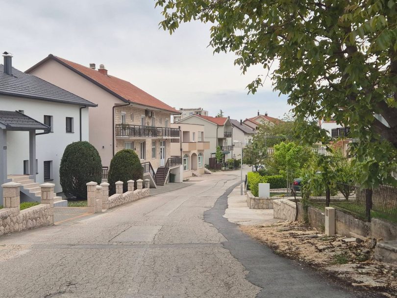Prikaz ulice Stjepana Radića s kućama i zasađenim stablima duž puta