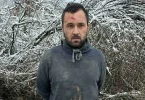 Muški osoba s bradом u sivoj majici ispred snježnog pejzaža tijekom istrage