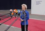 Žena u plavoj jakni govori pred mikrofonima na konferenciji o trgovinskim pregovorima