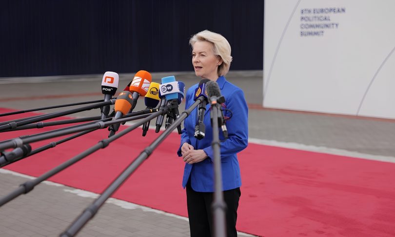 Žena u plavoj jakni govori pred mikrofonima na konferenciji o trgovinskim pregovorima