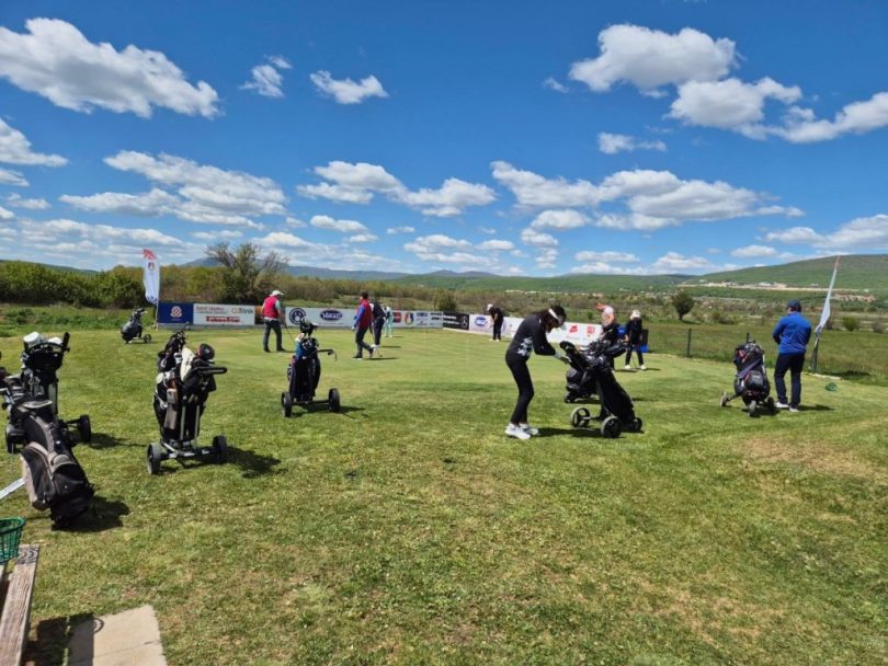 Golfers na travnatom igralištu tijekom turnira, sa planinama u pozadini