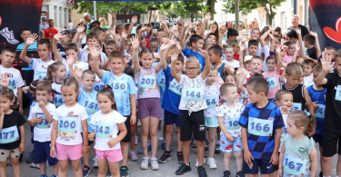 Grupa djece u sportskim dresovima na startnoj liniji trkačke utrke