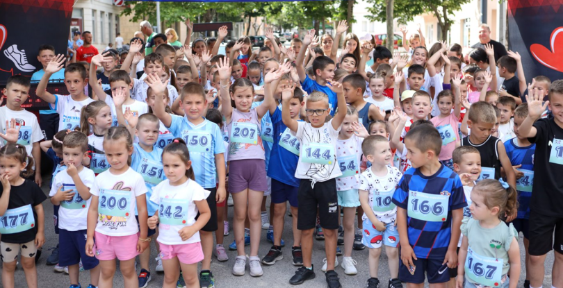 Grupa djece u sportskim dresovima na startnoj liniji trkačke utrke