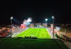 Noćno rasvjetljeni fudbalski stadion s viskom gledanja tijekom utakmice