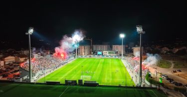 Noćno rasvjetljeni fudbalski stadion s viskom gledanja tijekom utakmice