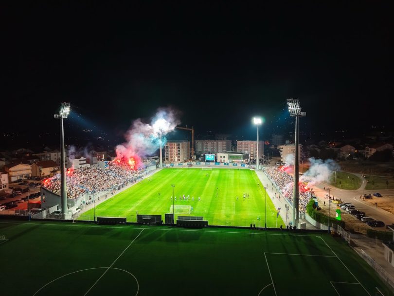 Noćno rasvjetljeni fudbalski stadion s viskom gledanja tijekom utakmice