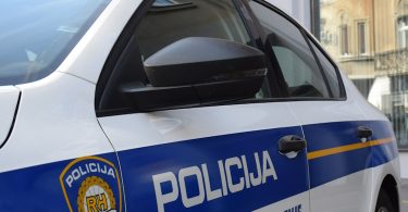 Policijsko vozilo s plavom svjetlosnom signalizacijom parkiran ispred zgrade