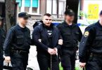 Policajci vode muškarca u civilu tijekom policijske akcije na gradskoj ulici