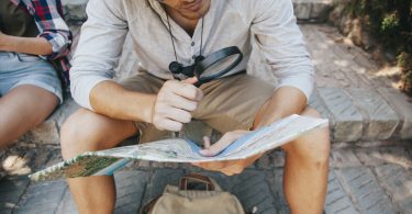 young traveler with map loupe