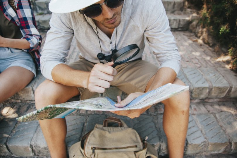 young traveler with map loupe
